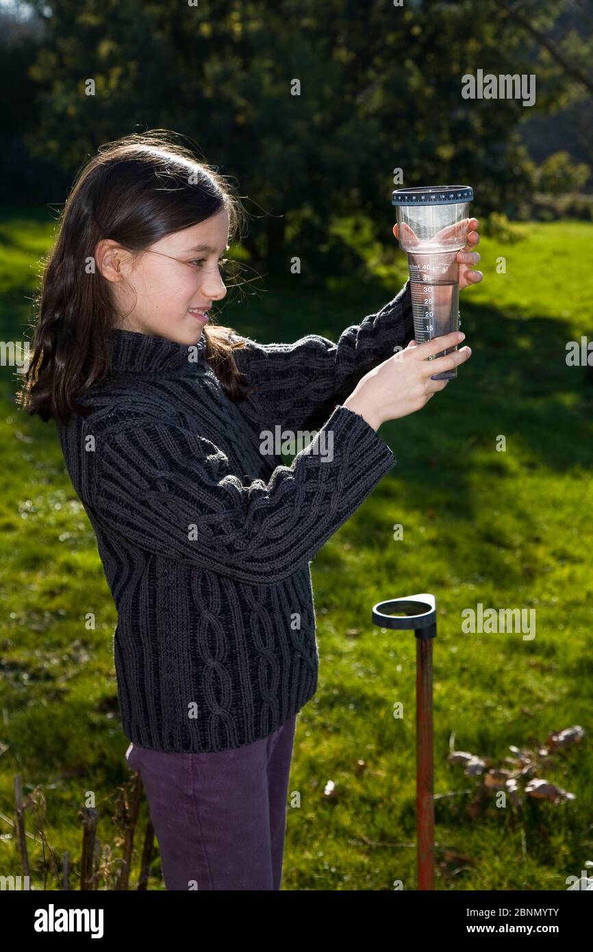 Jeune fille vérifiant un pluviomètre dans un jardin. Bretagne. France. Modèle libéré Banque D'Images