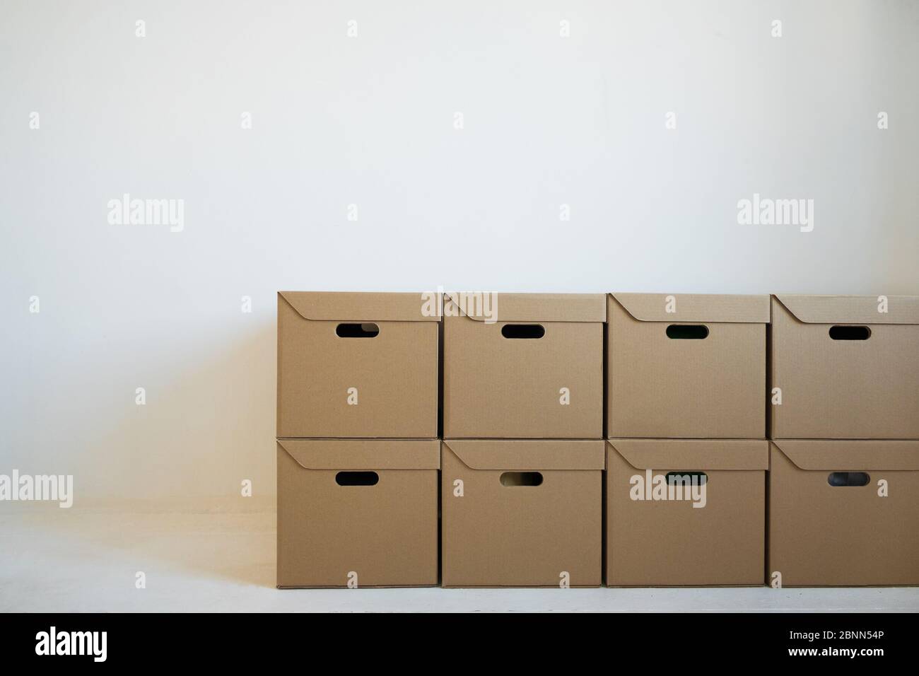 Boîtes en carton pour le stockage qui sont soigneusement empilées contre un mur blanc. Concept de livraison. Banque D'Images