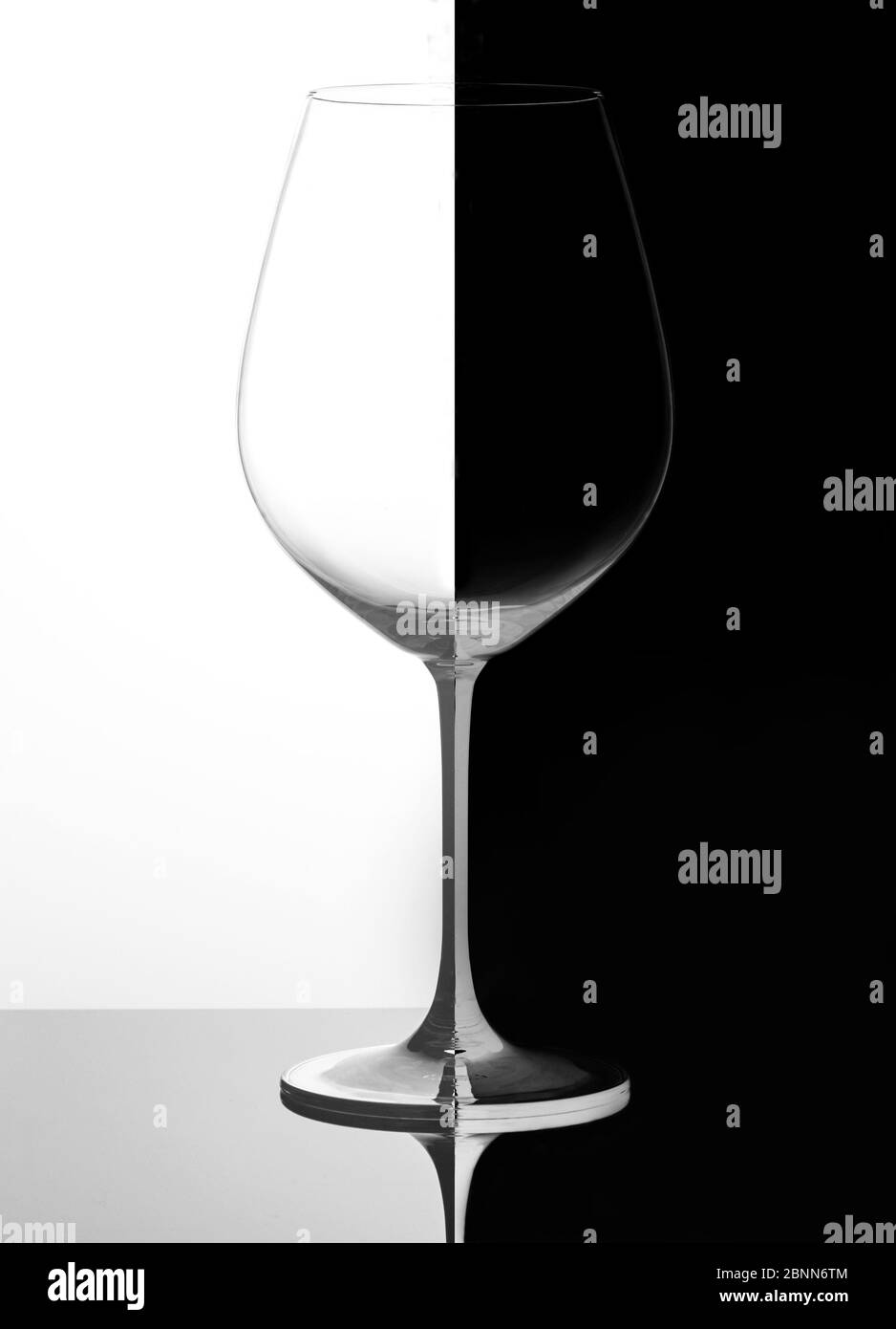 Verre de vin sur fond noir et blanc, avec reflet. Concept Domino. Banque D'Images