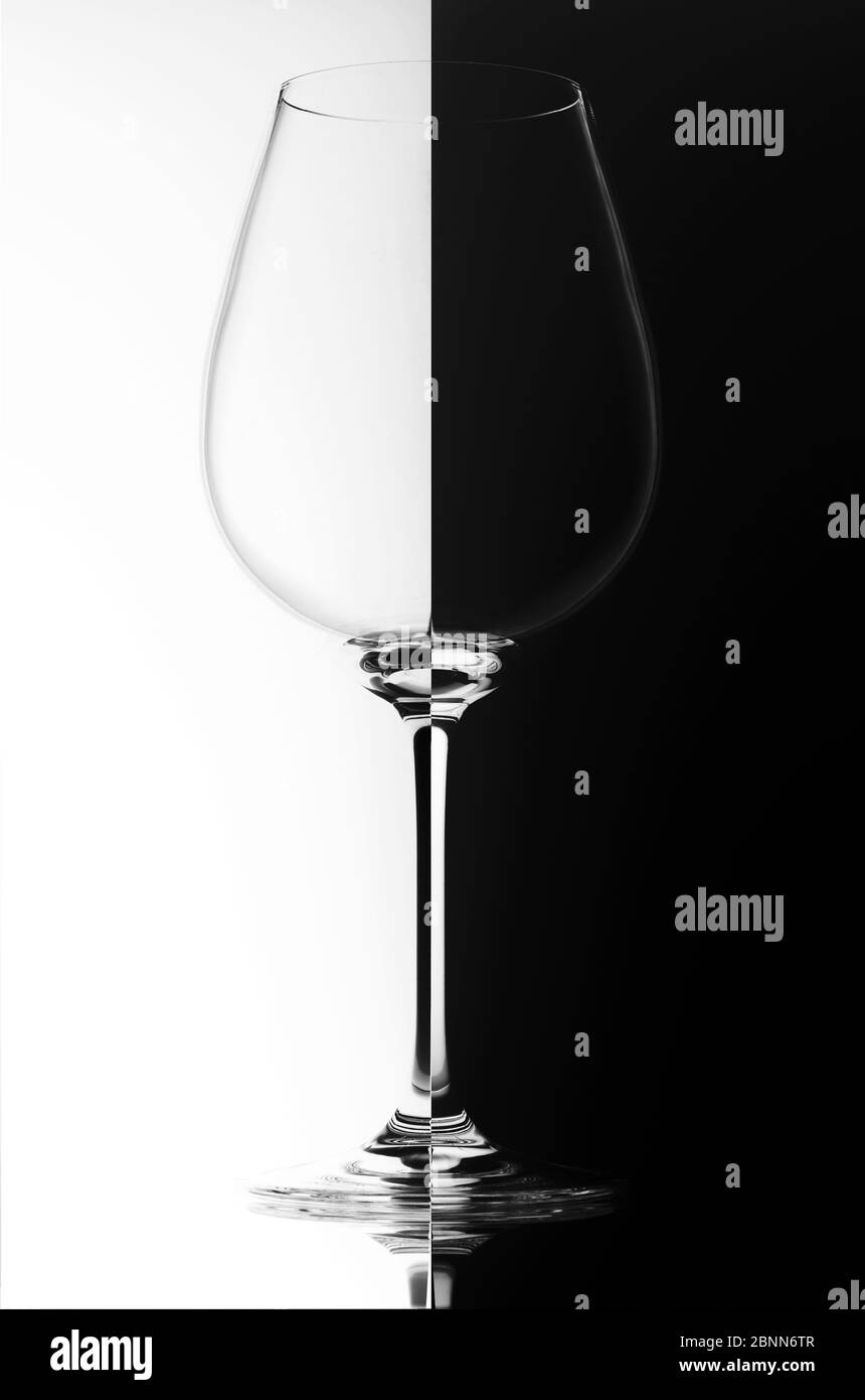 Verre de vin sur fond noir et blanc, avec reflet. Concept Domino. Banque D'Images