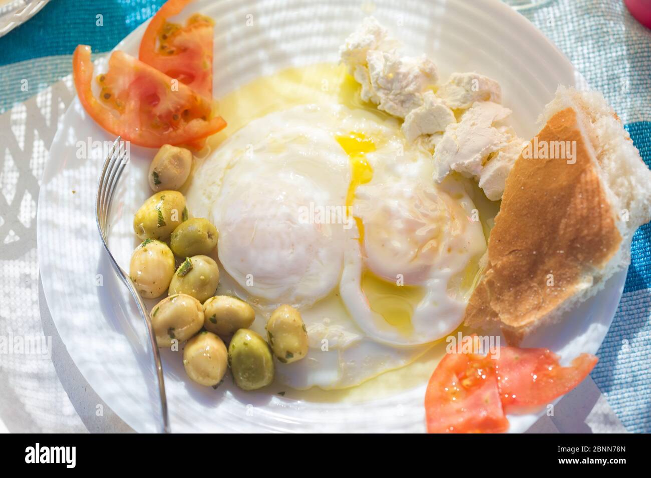 Œufs cuits pochés au fromage de chèvre, tomates et olives, petit déjeuner marocain Banque D'Images