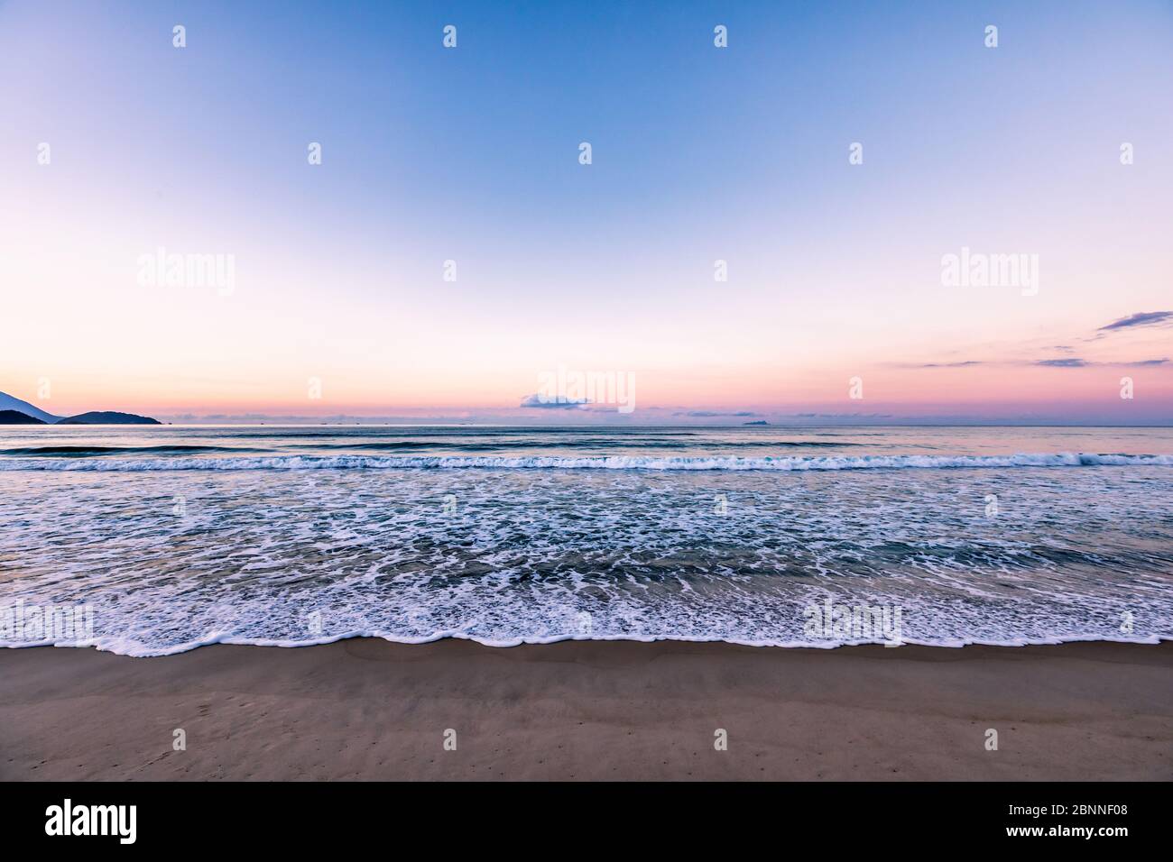 Coucher de soleil sur la plage avec de petites vagues se brisant de près Banque D'Images