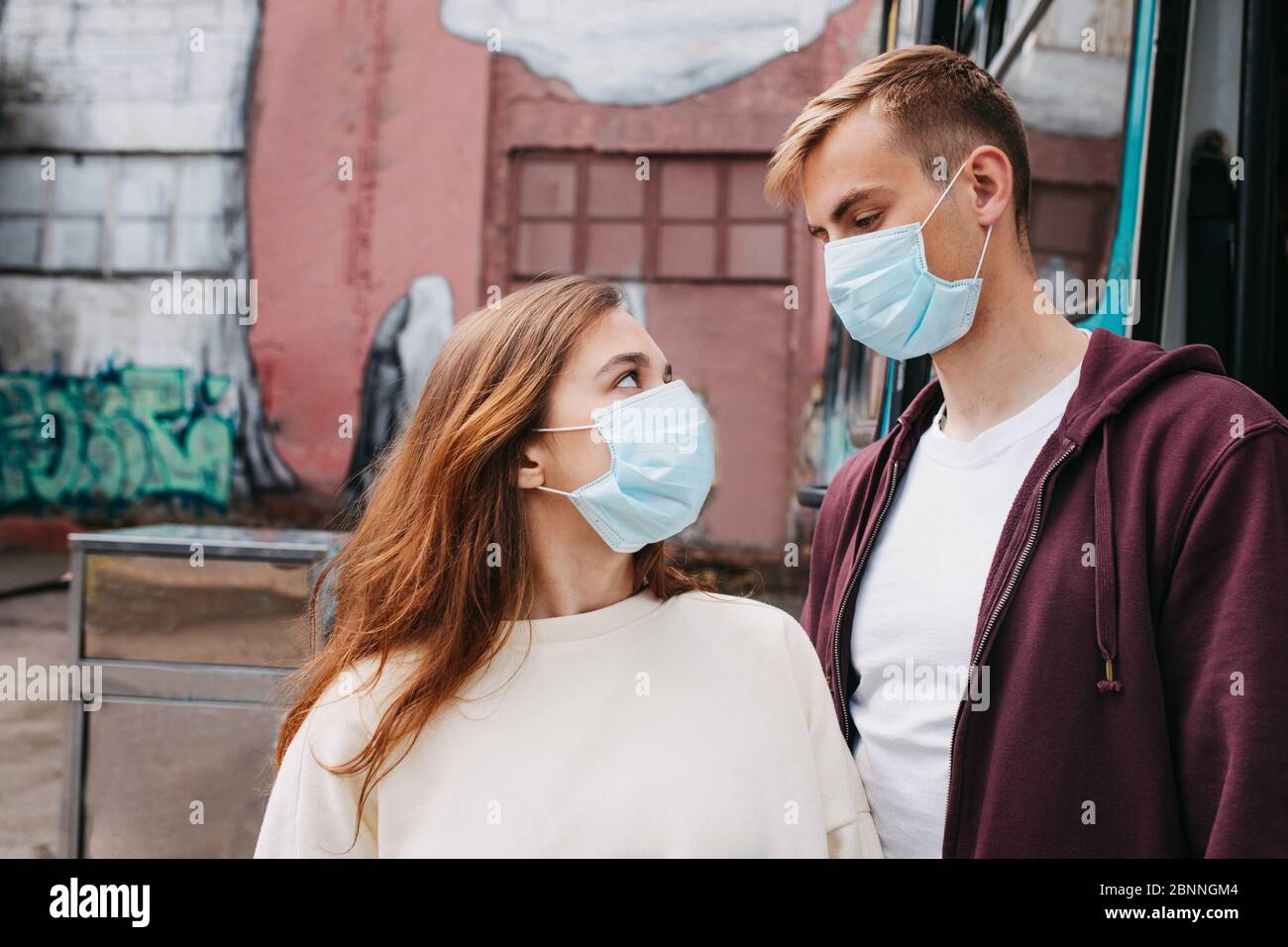 Jeune couple aimant portant des masques de visage dans la rue Banque D'Images