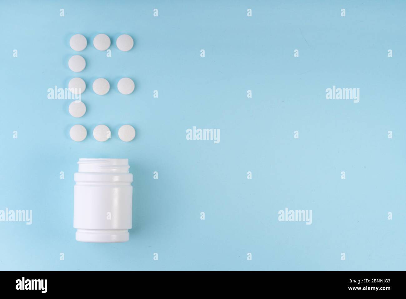 Les pilules de vitamine E ont chuté de la bouteille sur bleu. Inscription de la lettre E sur les comprimés. Vitamine E concept. Concept de protection de l'immunité, prévention antivirale. Banque D'Images