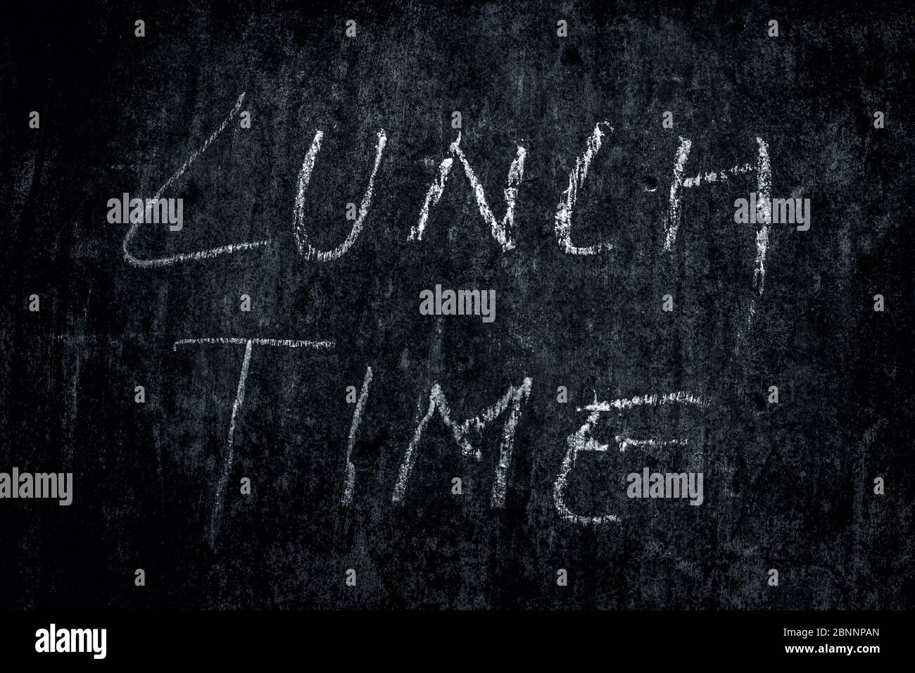 L'heure du déjeuner a écrit sur un mur de texture rugueuse avec de la craie blanche, photo horizontale. Banque D'Images