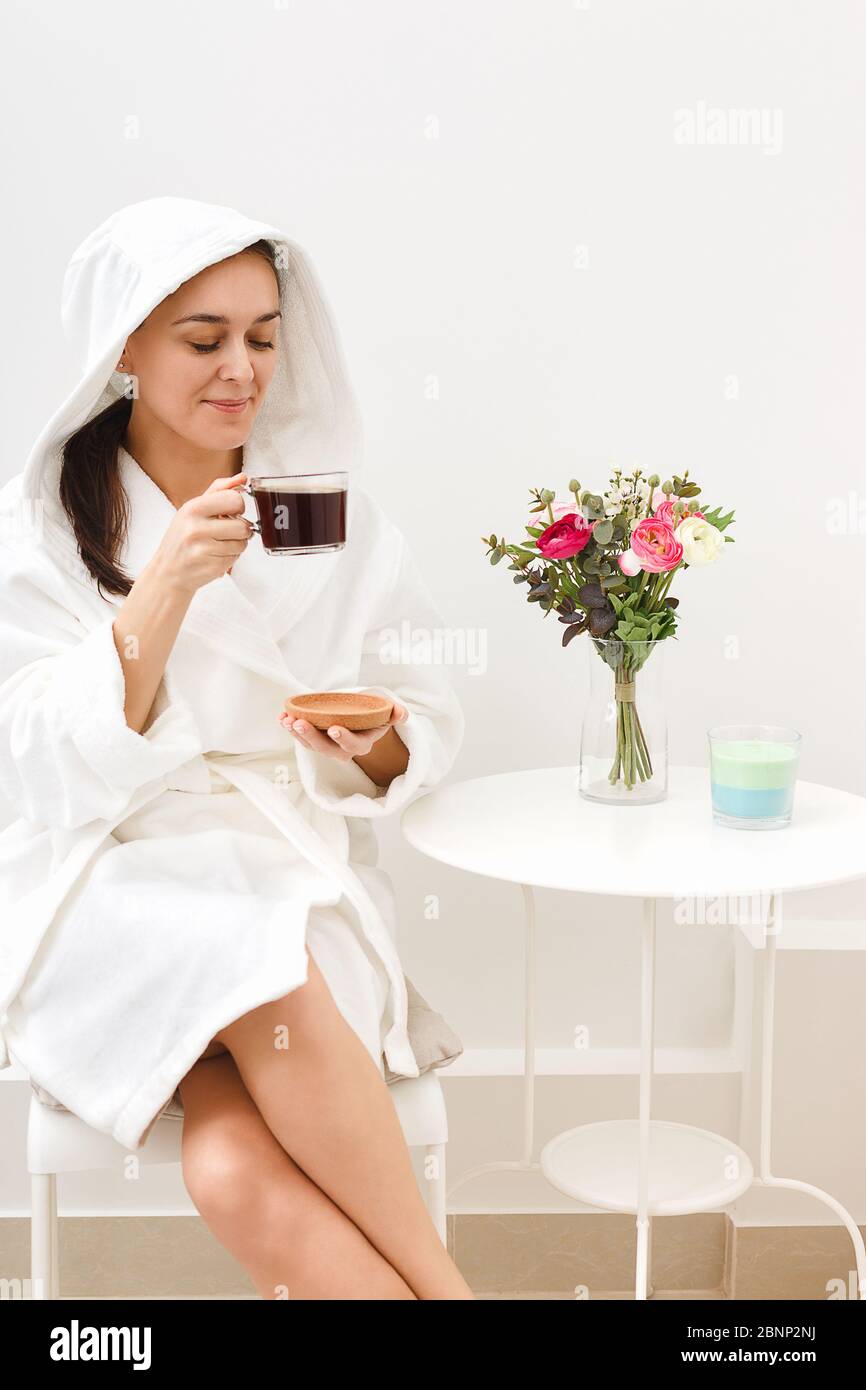 Une jeune fille boit du café dans une salle de relaxation située dans un salon de beauté après des soins de beauté ou un sauna spa. Le concept de soins et de client-orienté se Banque D'Images
