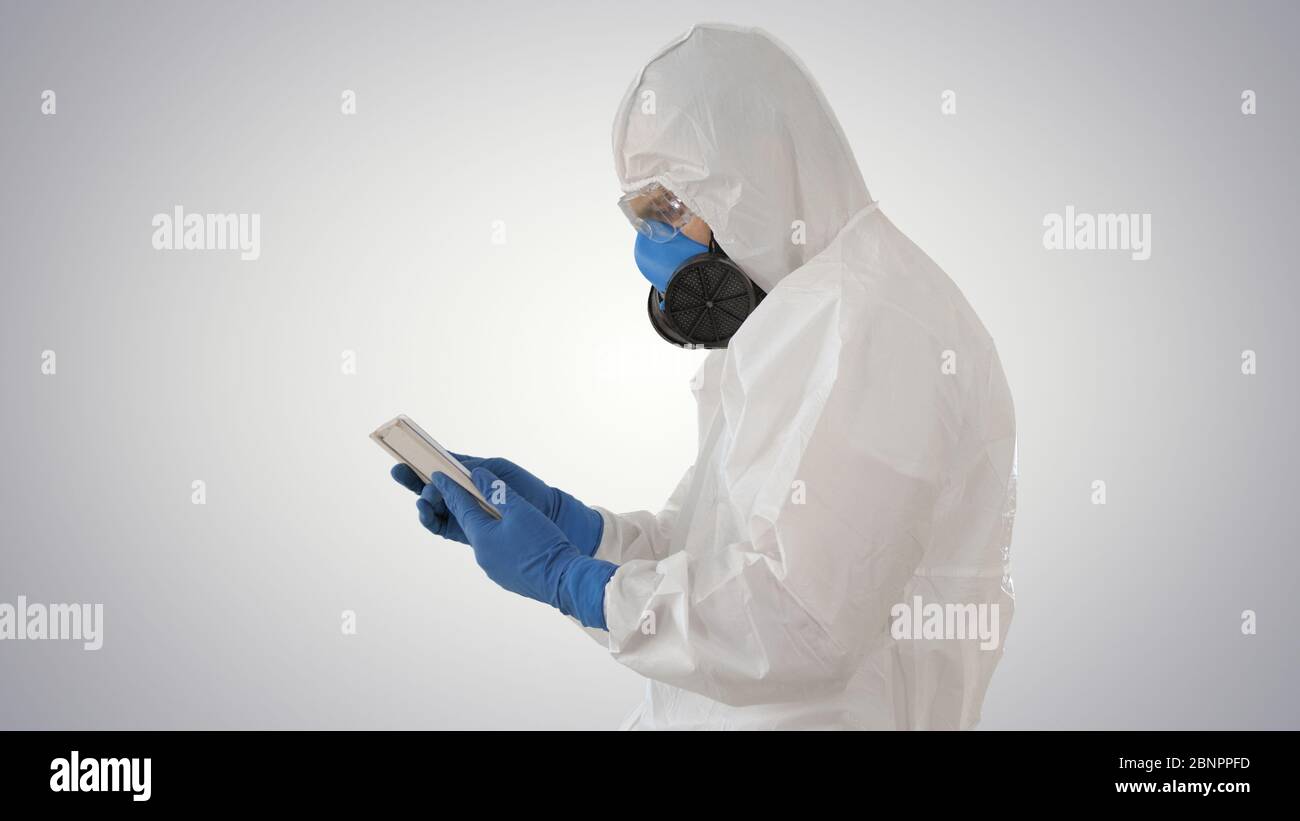 Médecin en costume de protection avec tablette numérique, concept Covid-19 sur fond dégradé. Banque D'Images