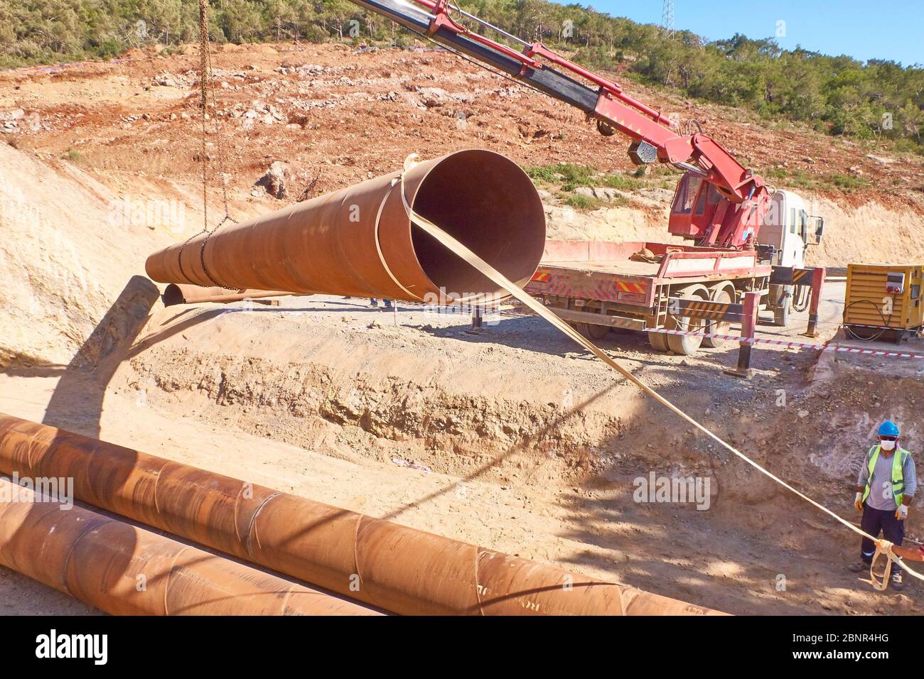 Les travailleurs pontent des ponceaux métalliques sous la route en cours de construction. Banque D'Images