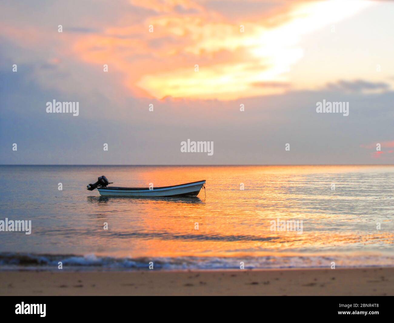 Un seul hors-bord à bord d'un bateau à moteur au coucher du soleil sur l'île Inhaca dans la baie de Maputo, au Mozambique, photographié avec un filtre pour s'assurer que seul le bateau est bien au point Banque D'Images