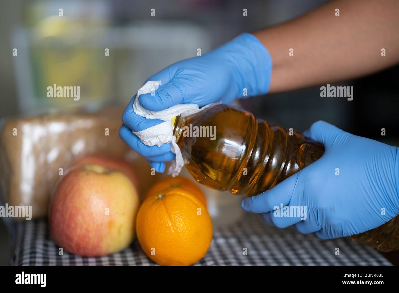 Une femme portant des gants nettoie une bouteille de jus de fruits pendant la pandémie COVID-19 2020 Banque D'Images