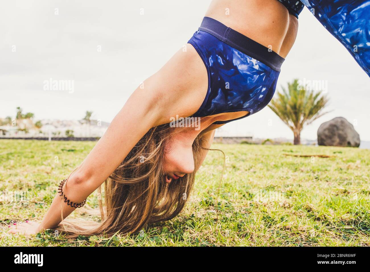 Gros plan de la forme physique saine femme dans le sport Pilates activité au parc sur la nature verte prairie - les gens et l'entraînement outdor - le style de vie actif pour la jeune femme avec les cheveux longs Banque D'Images