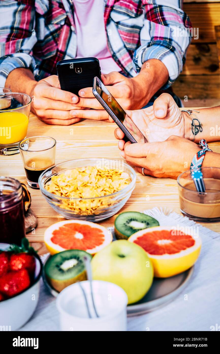 Gros plan sur les personnes avec un smartphone moderne connecté pendant le petit déjeuner, asseyez-vous sur la table - fruits frais et savoureux de couleur et café expresso italien pour un style de vie sain Banque D'Images