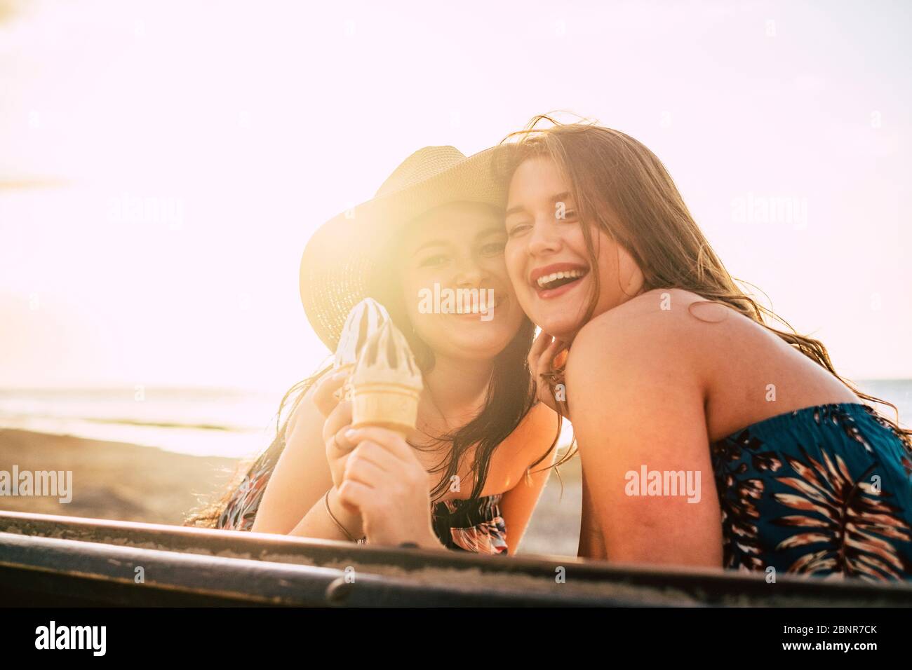 Joyeuse et le bonheur concept avec des gens joyeux couple heureux de jeunes filles caucasiennes avec la glace et l'été fond ensoleillé à la plage pendant les vacances Banque D'Images