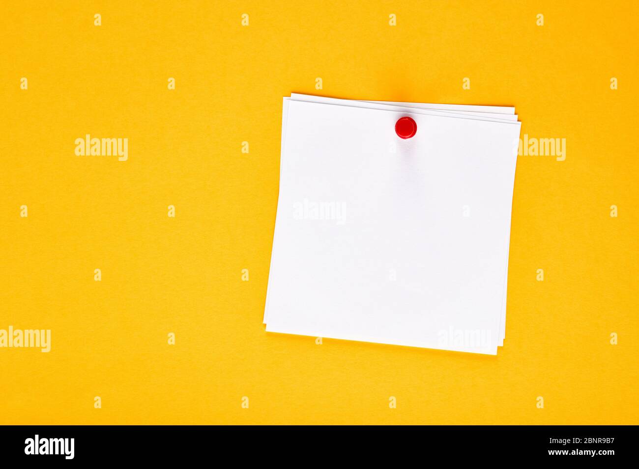 Papier vierge blanc épinglé à l'aide d'une épingle sur un panneau d'affichage jaune Banque D'Images