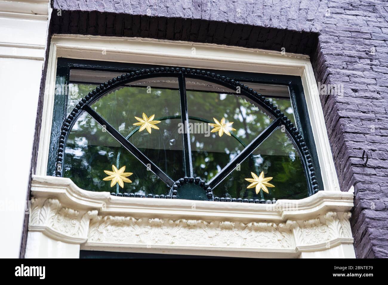 Porte classique décorée avec des étoiles dorées d'une ancienne maison traditionnelle penchée dans la vieille ville d'Amsterdam, pays-Bas Banque D'Images