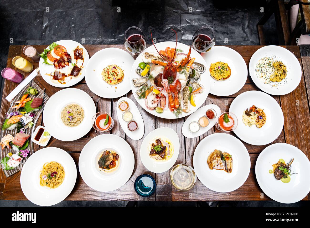 Vue sur le plan de table variété de plats internationaux de qualité dans le restaurant de crevettes de homard steak boeuf agneau pâtes spaghetti risotto riz sushi sashimi et wi Banque D'Images