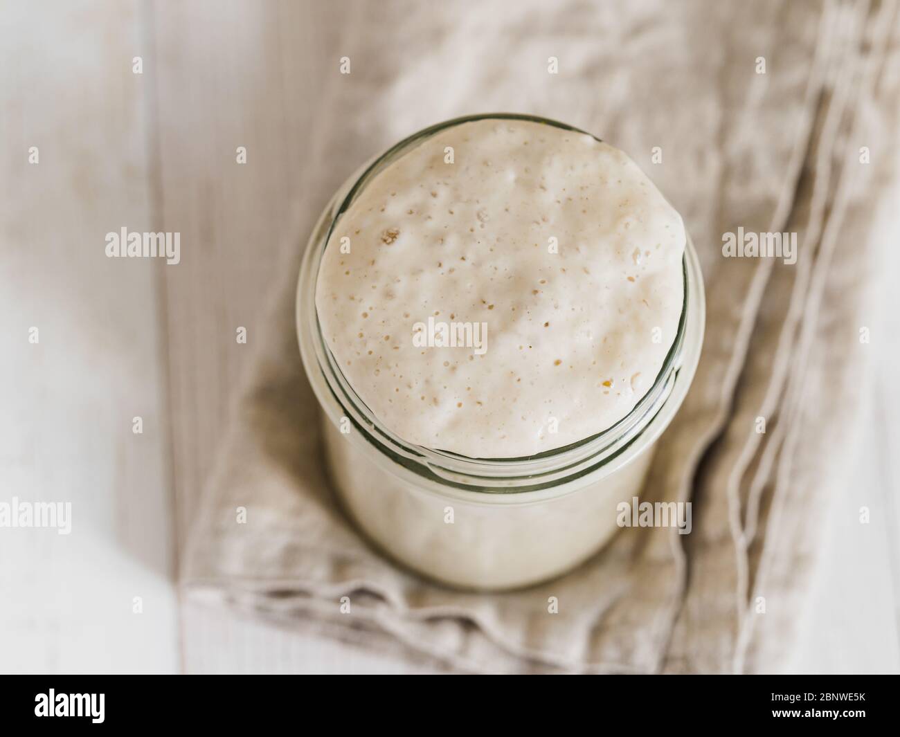 Démarreur de levain de blé. Vue de dessus du bol en verre avec démarreur de levain sur fond de bois blanc. Copier l'espace pour le texte ou la conception. Banque D'Images