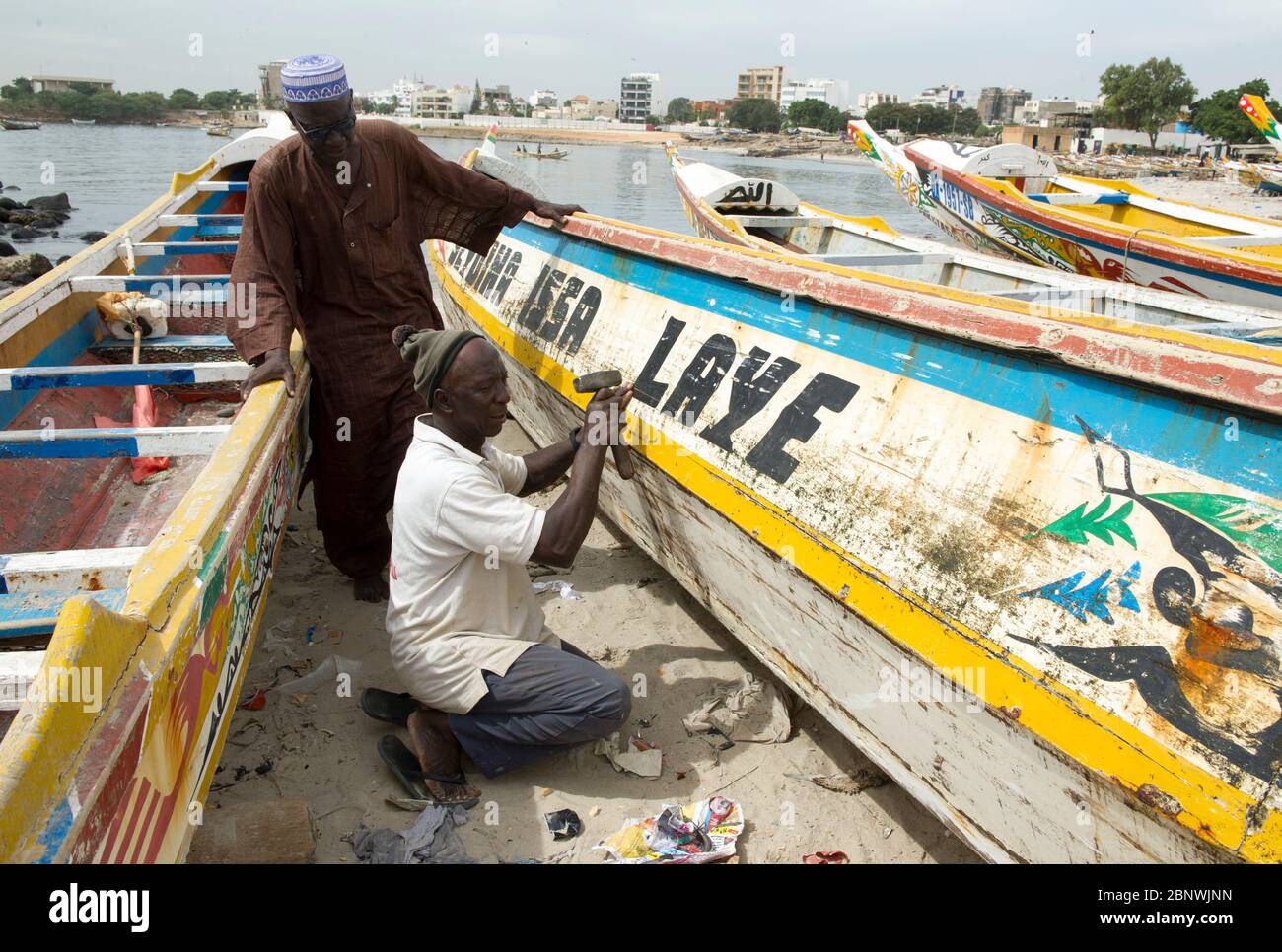 Hommes réparant un bateau de pêche traditionnel Pirogue sur la plage de Soumbedioune, Dakar, Sénégal. Banque D'Images