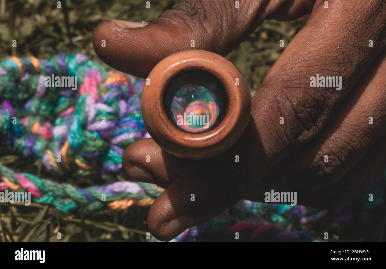 Une personne tenant un pot fumant pipe, également connu sous le nom de Chillum, la résection du porte-pipe coloré (placé à l'arrière) peut être vu sur l'intérieur t Banque D'Images