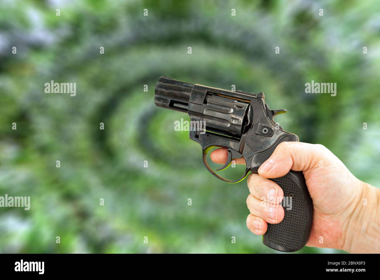 Pistolet en main sur fond vert flou sous forme de spirale Photo Stock -  Alamy