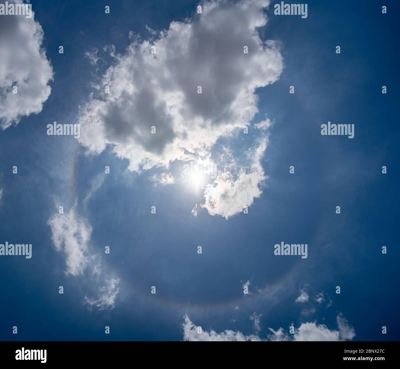 Photo d'un halo solaire visible dans le ciel. Un cercle de couleur avec le soleil au centre et quelques nuages de cirrus autour Banque D'Images