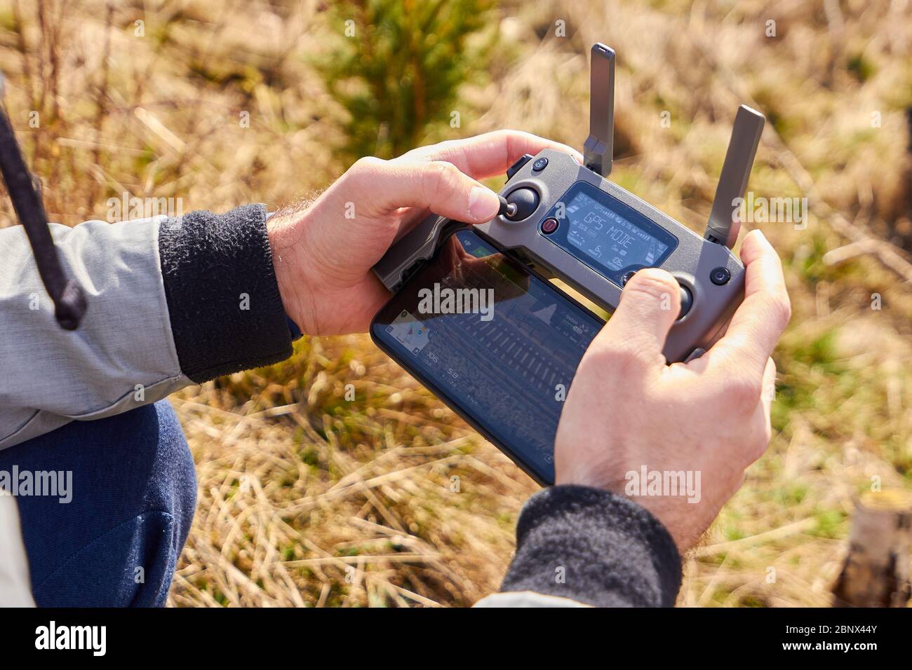 Gros plan les mains tenant la télécommande de drone avec smartphone sur le terrain. Concept de tir et de vol aérien, San Francisco, mai 2020. Banque D'Images
