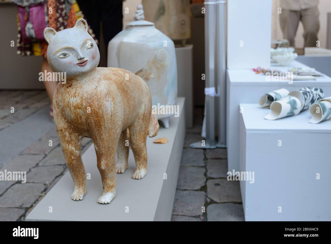 Lyon, France : une figurine de chat en céramique à visage humain sur le marché des arts de la place Saint-Jean par la cathédrale de Lyon (Cathédrale Saint-Jean-Baptiste). Banque D'Images