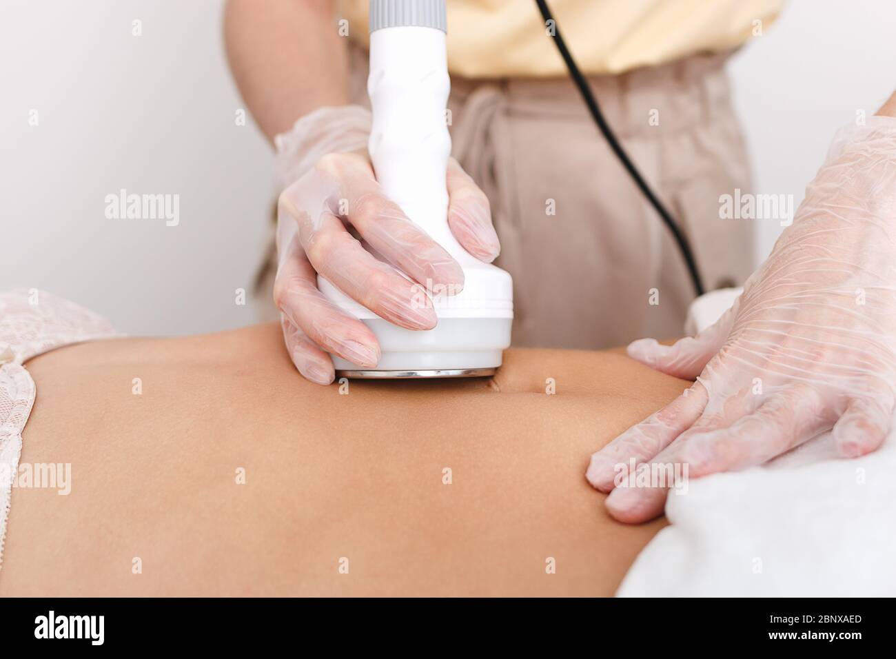 Le cosmétologue fait la cavitation de l'abdomen du modèle, la correction matérielle de la figure, la destruction de l'excès de poids, ou les cellules graisseuses. STU Banque D'Images