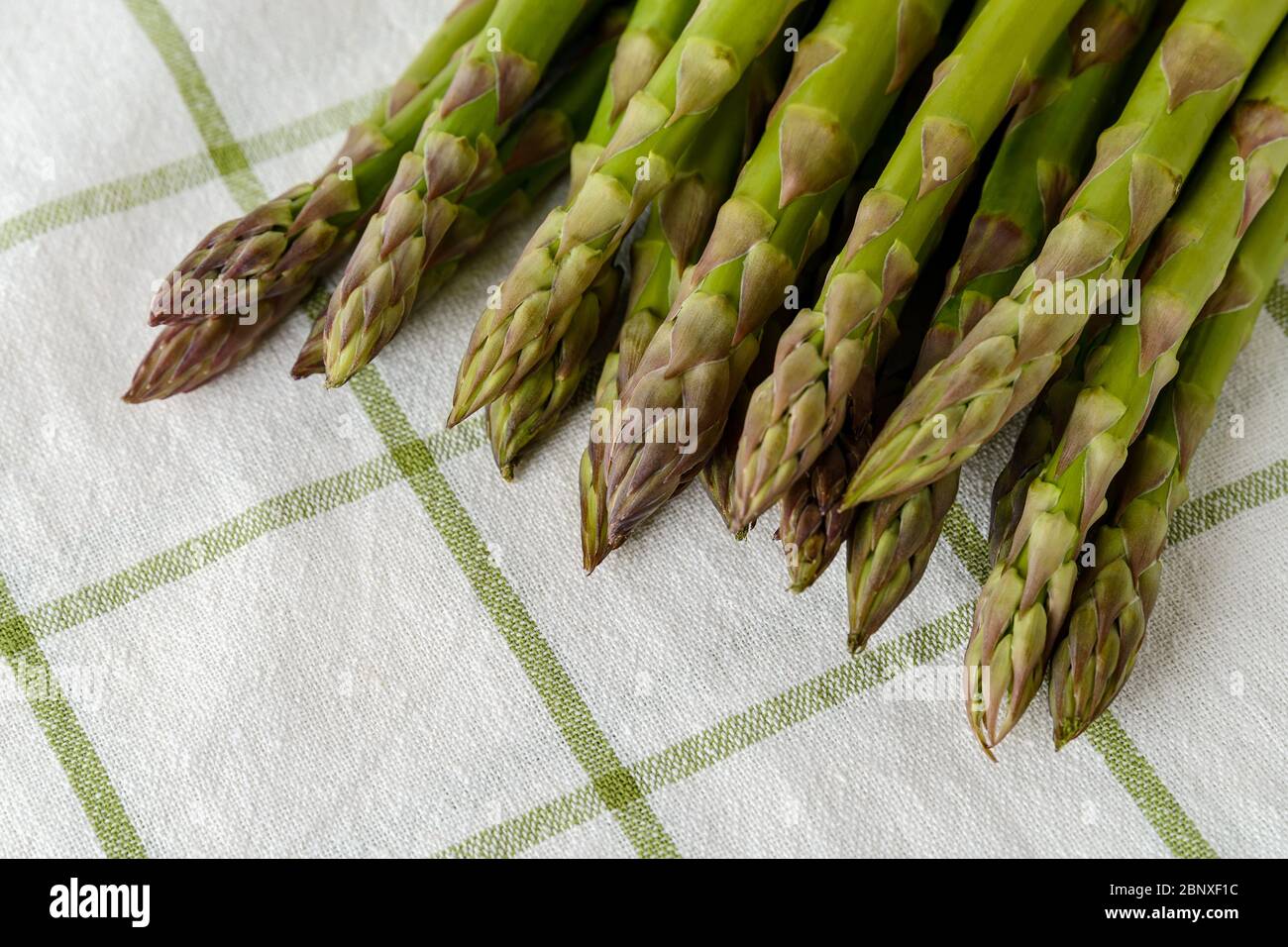 Bouquet de tiges d'asperges vertes fraîches sur une serviette de cuisine blanche. Ingrédient pour manger de la viande, régime végétarien et alimentaire cru. Gros plan. Banque D'Images