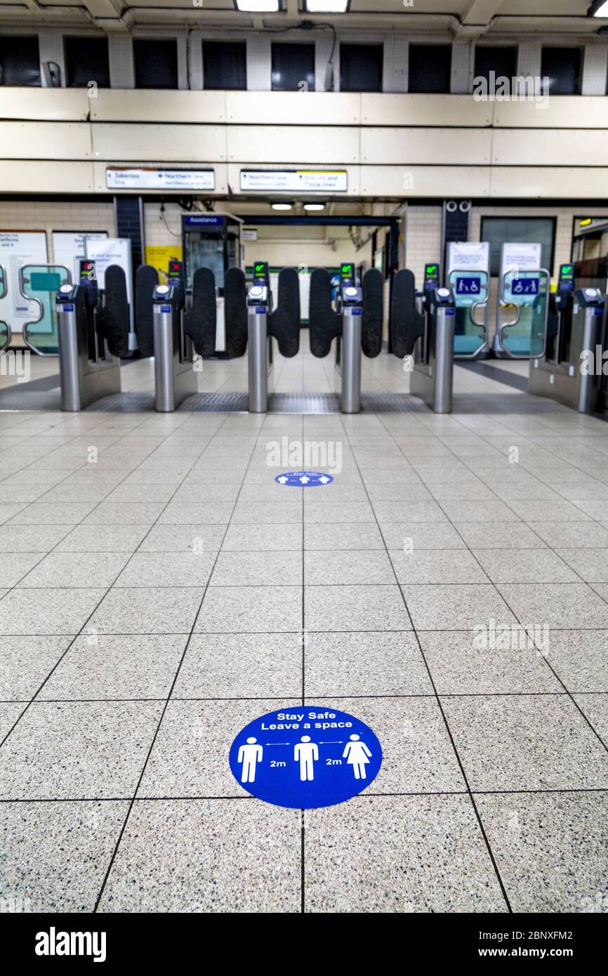 16 mai 2020 Londres, Royaume-Uni - des panneaux sur le sol à la station d'Embankment pour rappeler aux gens de garder une distance de 2 m lors de l'entrée dans le métro pendant le confinement en cas de pandémie du coronavirus et les mesures de distanciation sociale Banque D'Images