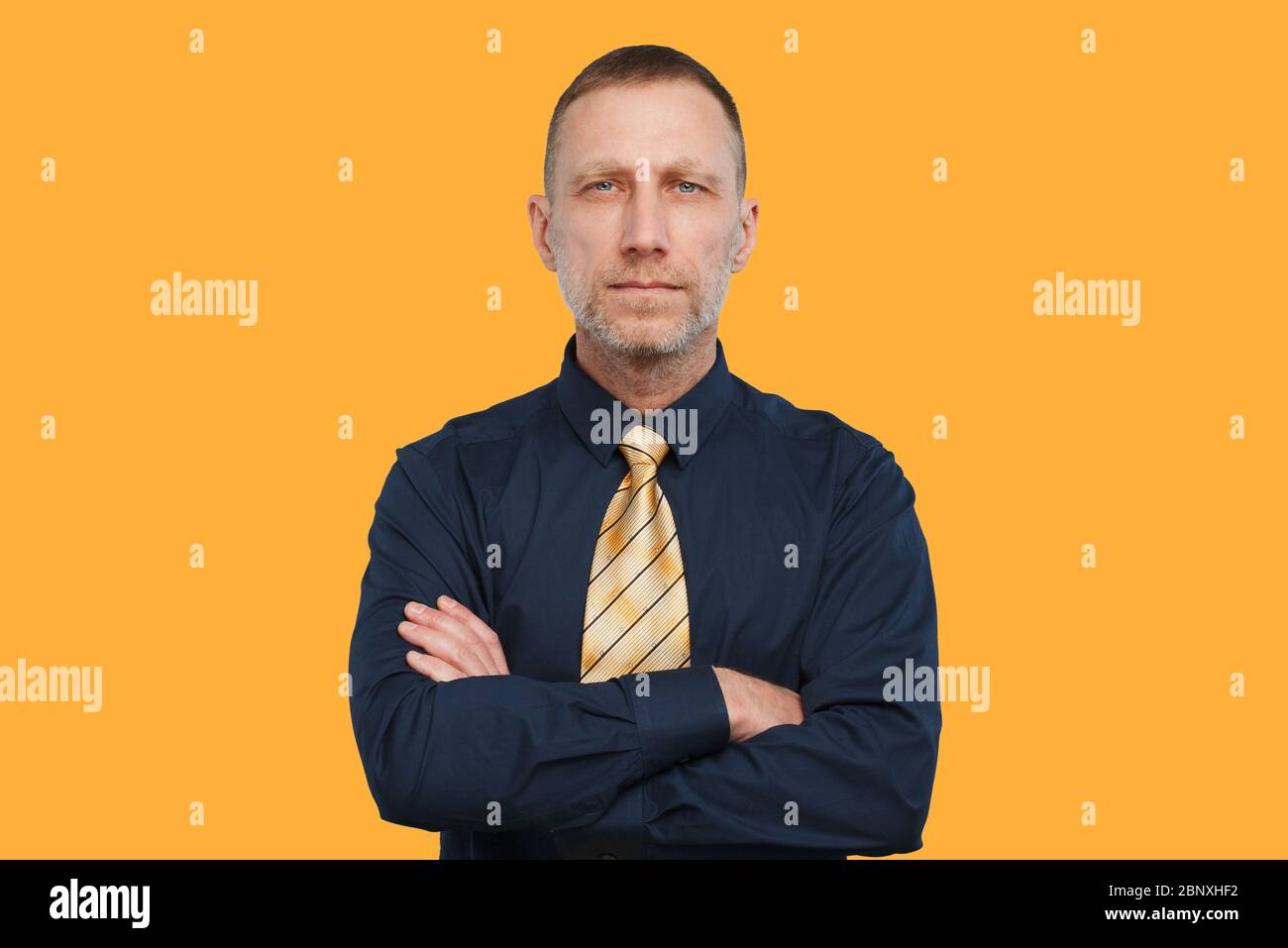 Homme dans une chemise bleu foncé et une cravate jaune vif et avec les bras  croisés sur un fond orange Photo Stock - Alamy