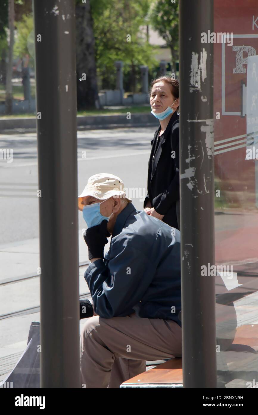 Belgrade, Serbie - 8 mai 2020 : les personnes âgées portant des masques chirurgicaux attendent les transports publics à l'arrêt de bus Banque D'Images