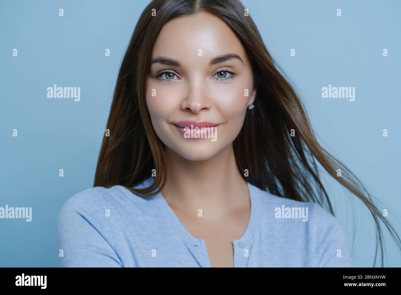 Prise de vue horizontale de la jeune femme avec des cheveux noirs droits, un look frais et un maquillage, se soucie de sa peau satisfait des produits de soin de la peau laisse positif c Banque D'Images