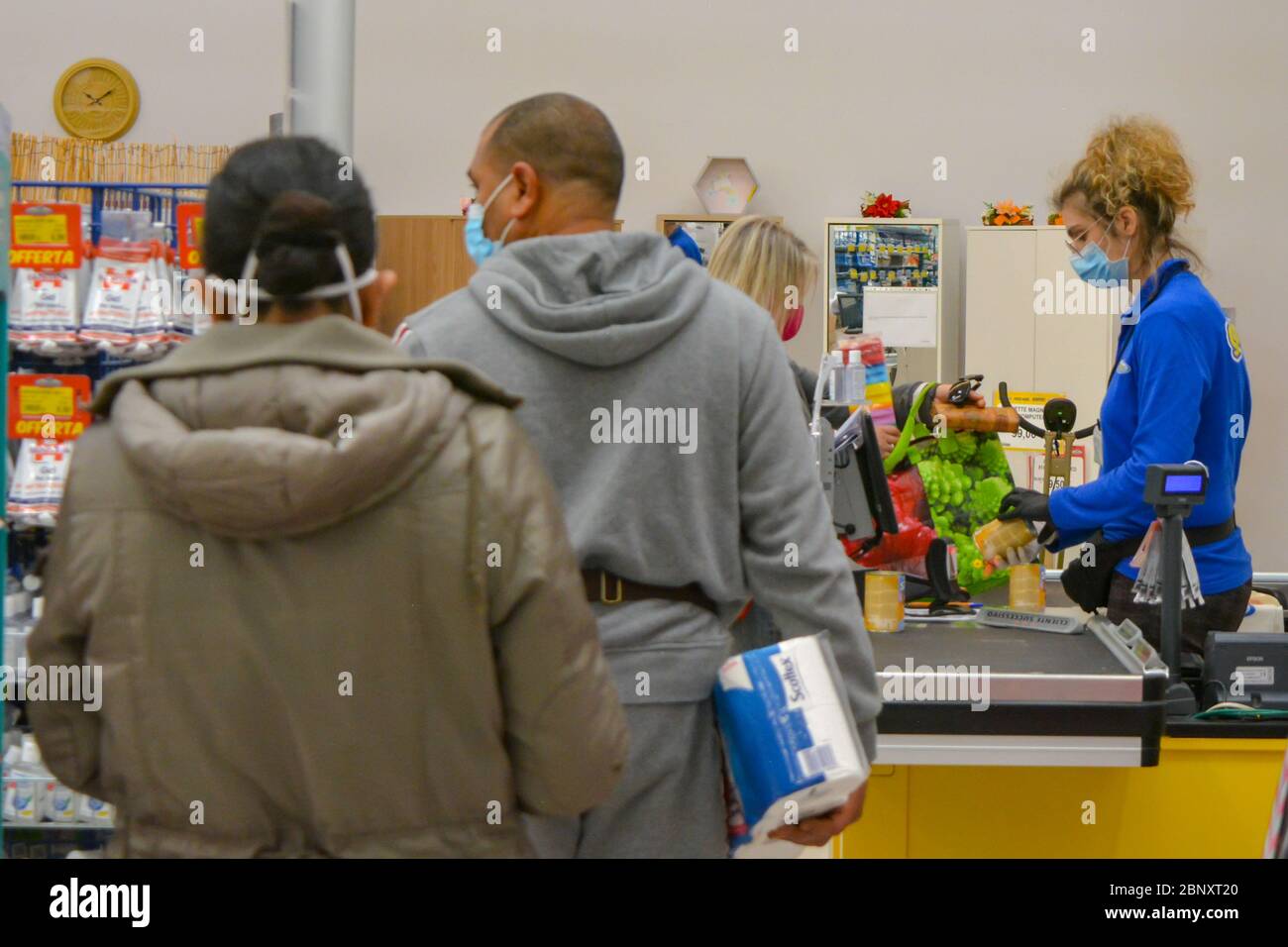 Toscane, Italie 04/14/20 UN caissier dans une épicerie portant un masque et des gants de protection contre les coronavirus, scannant du papier toilette et d'autres produits. Shoppin Banque D'Images