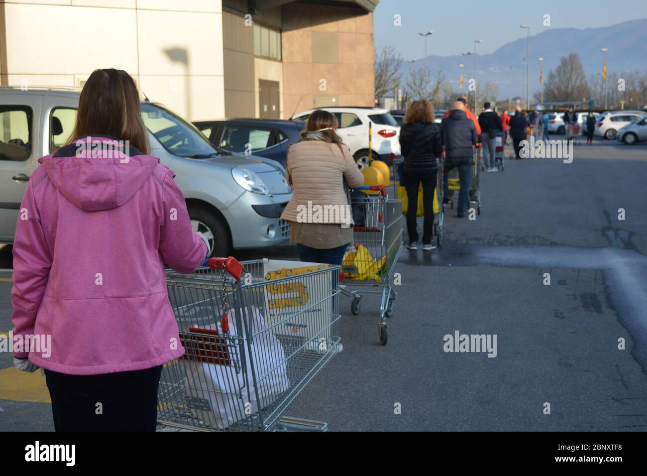 Réalité quotidienne pendant la pandémie du coronavirus : une longue file de personnes qui attendent avec patience, par temps ensoleillé, pour stocker des provisions. Réouverture des villes italiennes Banque D'Images