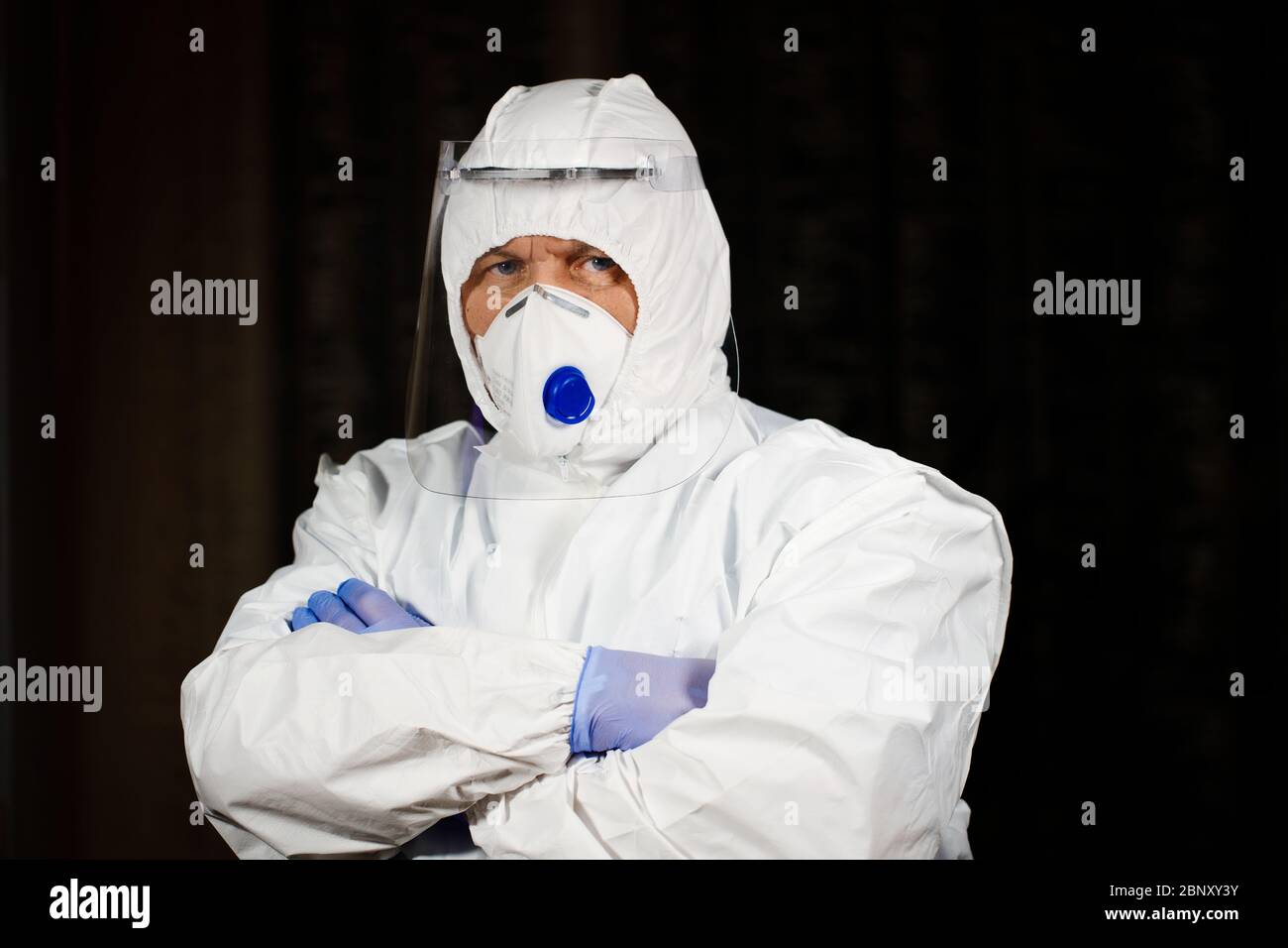 Un médecin sérieux en costume de protection et masque vous regarde Banque D'Images