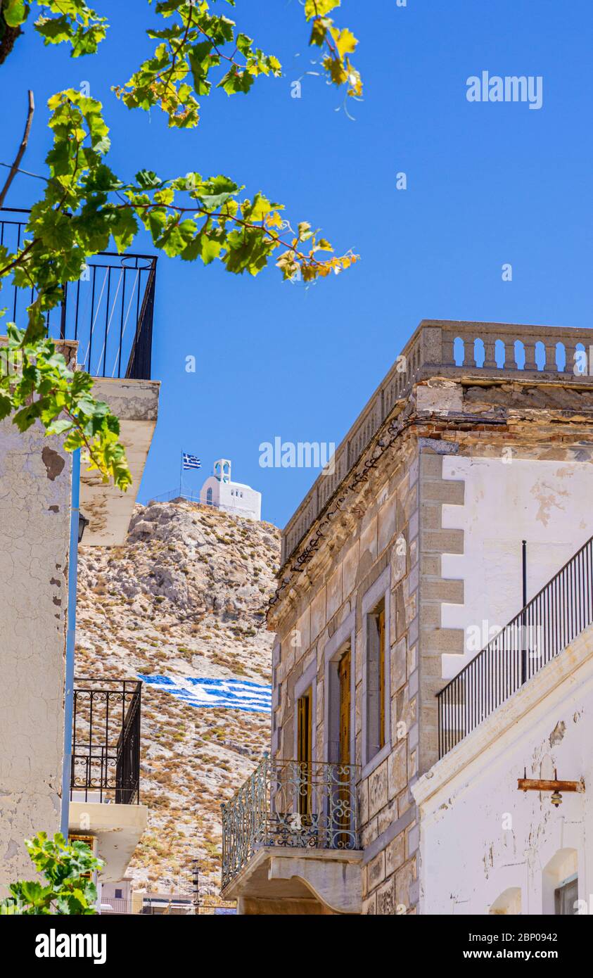 La petite église blanche sur la colline, vue à travers les bâtiments rustiques de Pothia Town, Kalymnos, Dodécanèse, Grèce Banque D'Images