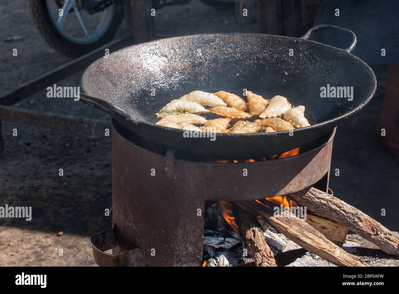 Wok cuisant avec de l'huile chaude sur petit brûleur à bois. Banque D'Images