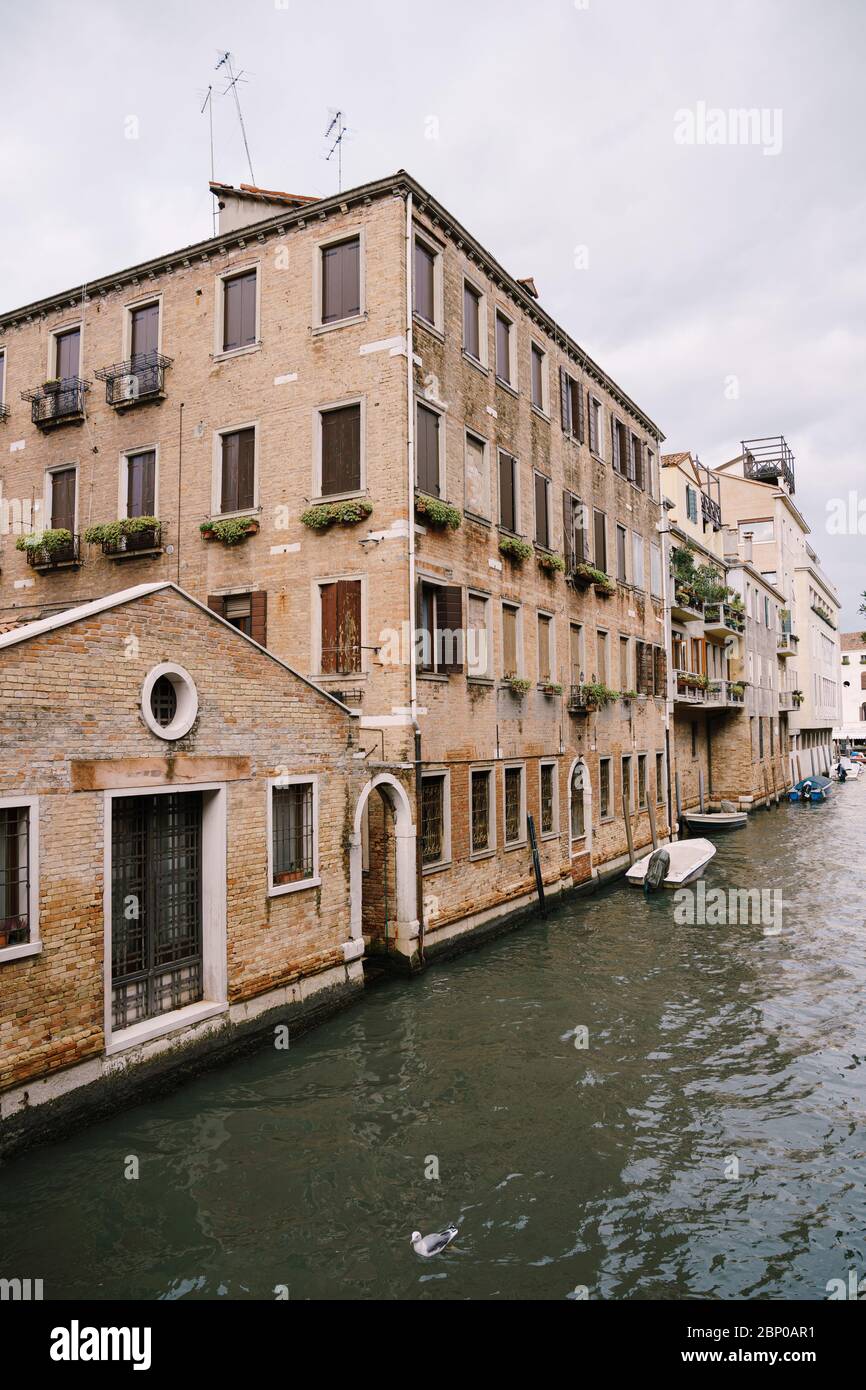 Des bateaux amarrés aux murs d'un bâtiment dans un canal à Venise, Italie. Vue sur la rue vénitienne classique - volets en bois, maisons en briques, ponts Banque D'Images