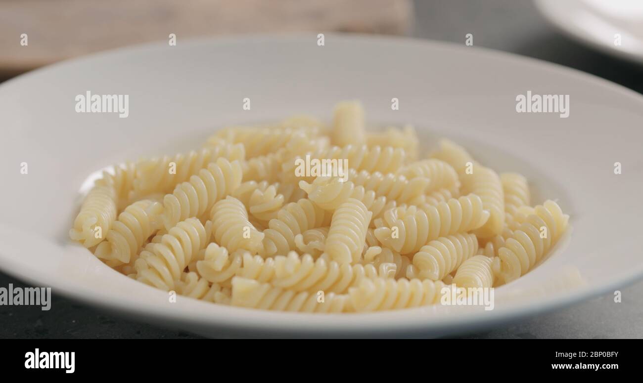 la vapeur s'élève du fusilli chaud bouilli dans la plaque blanche Banque D'Images