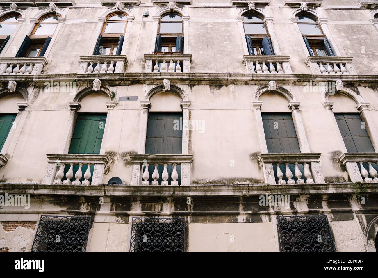 Gros plan de la façade d'un bâtiment, dans les rues de Venise, Italie. Bâtiment en pierre blanche avec fenêtres vénitiennes voûtées classiques et volets en bois. Banque D'Images