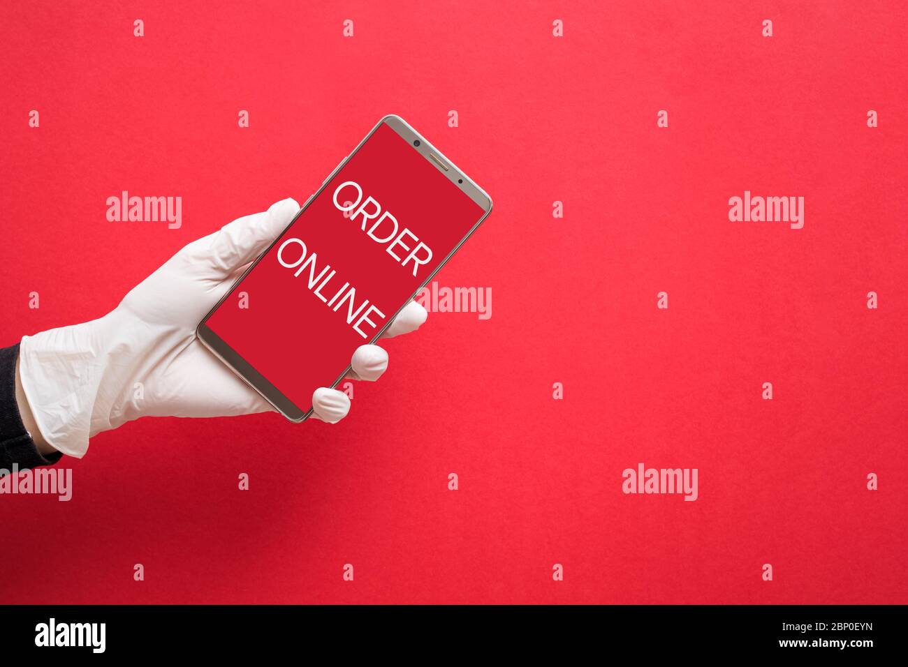 Main dans un gant de protection blanc tenant un smartphone avec texte Commander en ligne Banque D'Images