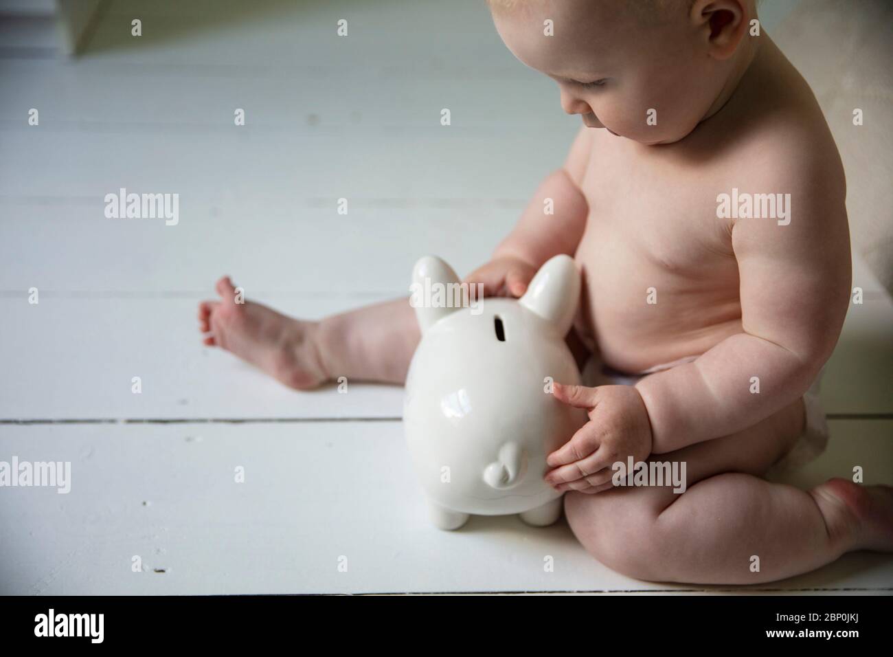 Un bébé tenant sur une banque de pigeons. Coût de l'éducation d'un concept d'enfant Banque D'Images