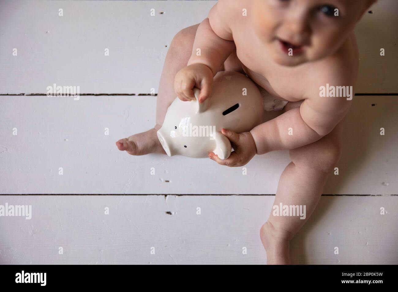 Un bébé tenant dans une boîte de monnaie de l'interdiction de la pigey. Concept des frais de garde d'enfants Banque D'Images