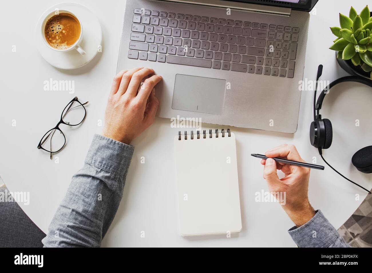 Homme travaillant sur un ordinateur portable et buvant du café sur son lieu de travail. Bureau à domicile, vue du dessus Banque D'Images