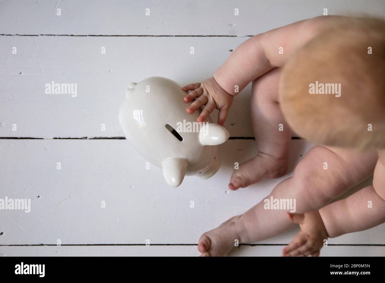 Un bébé tenant dans une boîte de monnaie de l'interdiction de la pigey. Concept des frais de garde d'enfants Banque D'Images