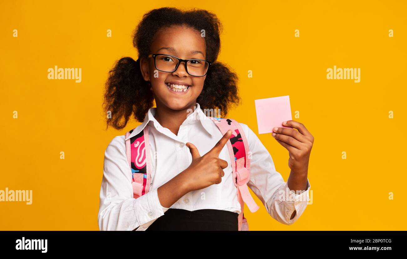 École fille pointant le doigt à vide carte papier, Studio Shot Banque D'Images