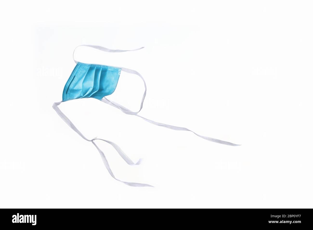 Masque bleu tombant avec fond blanc et masque de protection contre le virus corona. Banque D'Images