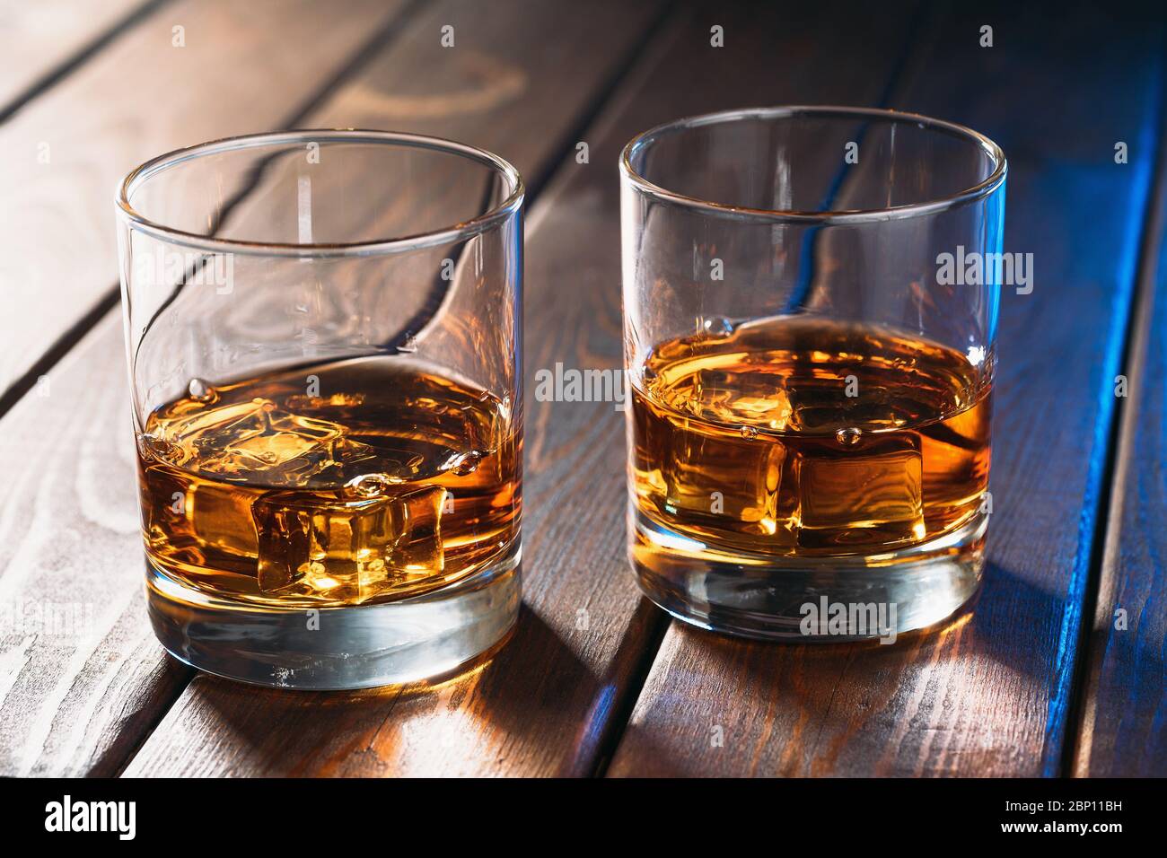 Verres avec whisky ou autre boisson alcoolisée sur table en bois vintage, gros plan. Banque D'Images