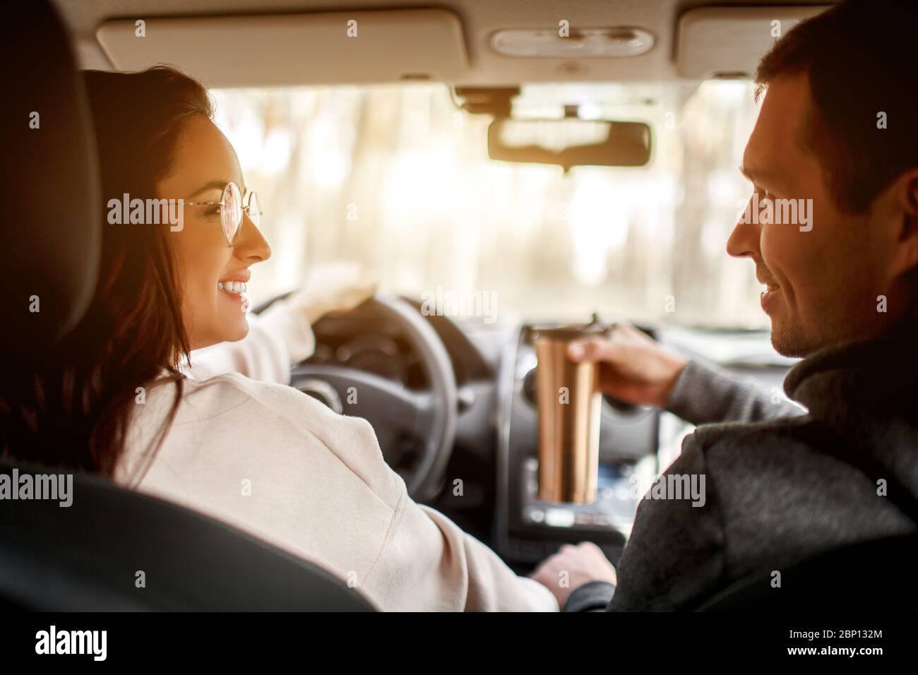 Une famille heureuse se déplace en voiture dans la forêt. Une femme conduit une voiture et un homme est assis à proximité. Concept de voyage en voiture. Banque D'Images